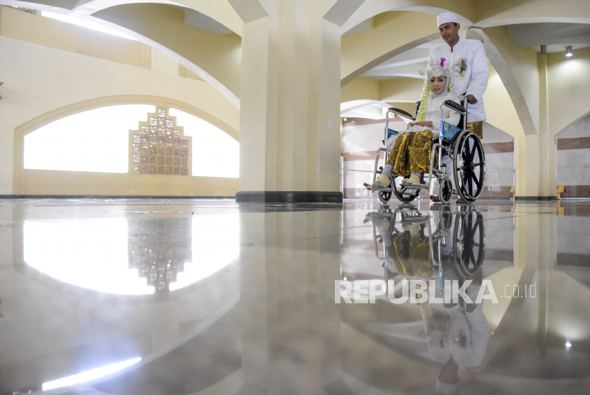 Pasangan pengantin difabel berjalan keluar ruangan usai prosesi akad pada kegiatan Nikah Massal Difabel di Masjid Pusdai, Kota Bandung, Kamis (2/12). Nikah Massal yang diikuti oleh 13 pasangan difabel tersebut digelar dalam rangka memperingati milad Pusdai Jabar yang ke-24 sekaligus Hari Disabilitas Internasional 2021. Foto: Republika/Abdan Syakura