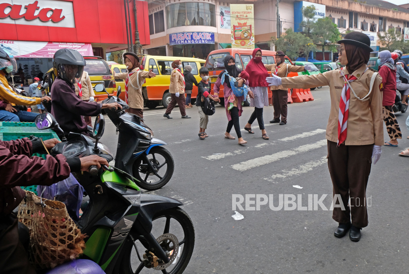 Anggota Pramuka membantu warga menyeberang jalan saat mengatur lalu lintas di kompleks pasar Kliwon Temanggung, Jawa Tengah. Sejumlah anggota Pramuka diterjunkan untuk membantu petugas mengatur lalu lintas di jalur mudik terutama di titik-titik rawan kemacetan. 