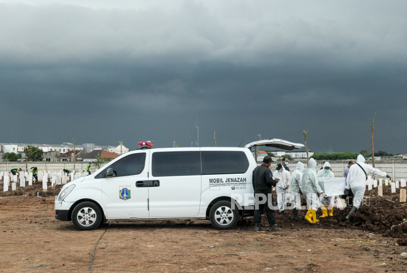 Petugas mengangkat peti jenazah pasien Covid-19 yang dikeluarkan dari ambulans. Pemprov DKI sudah mulai menggunakan truk mengangkut jenazah Covid karena ambulans kewalahan angkut ratusan jenazah per hari.