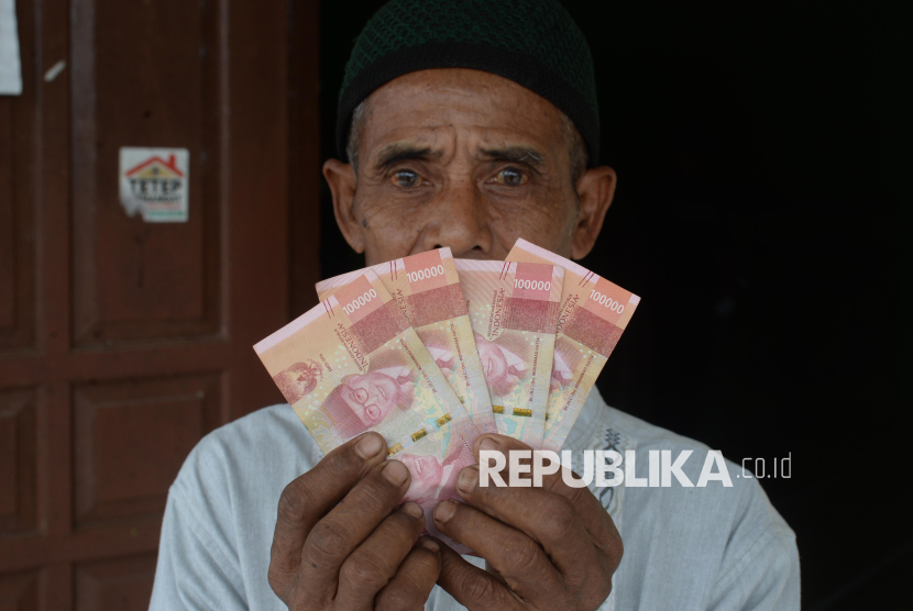 Warga menunjukan uang tunjangan hari raya (THR) yang diberikan oleh pemerintah desa di Kantor Desa Wunut, Tulung, Klaten, Jawa Tengah, Selasa (18/3/2025). Pemerintah setempat memberikan tunjangan hari raya untuk warganya sebesar Rp200 ribu per orang sebanyak 2.289 jiwa dengan total anggaran Rp457,8 juta yang diambil dari sumber dana hasil usaha BUMDES Sumber Kamulyan. 