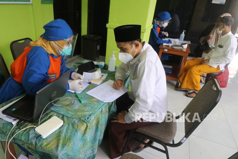 Petugas kesehatan membantu mengisi formulir sebelum menyuntikkan vaksin COVID-19 kepada pengasuh pondok pesantren (ponpes) Lirboyo di Kota Kediri, Jawa Timur, Jumat (26/2/2021). Sebanyak 49 orang pengasuh ponpes Lirboyo mendapatkan suntikan vaksin sebagai upaya menanggulangi penyebaran COVID-19 di lingkungan pesantren. 