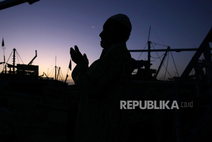 Siluet seorang nelayan berdoa setelah melaksanakan shalat Isya di atas kapal saat bulan puasa Ramadhan, di Karachi, Pakistan, (27/3/2023).