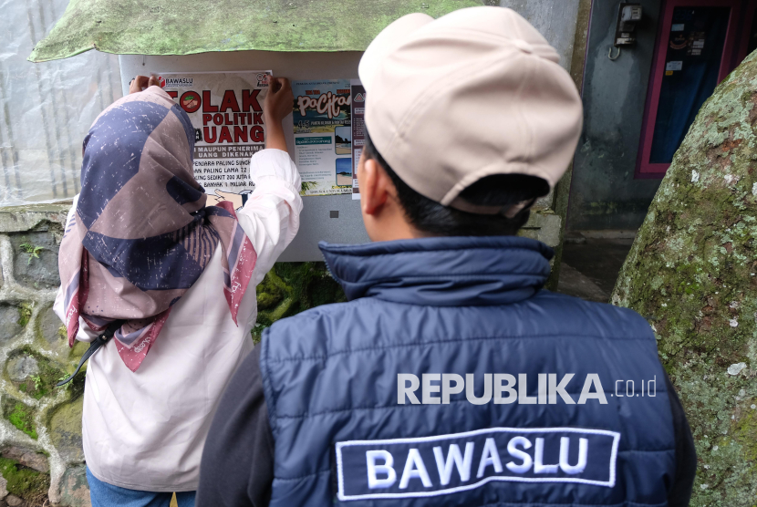 Anggota Bawaslu menempelkan poster saat sosialisasi tolak politik uang Pilkada 2024 di Brojolan, Temanggung, Jawa Tengah, Senin (25/11/2024). Bawaslu setempat memberikan pemahaman kepada masyarakat untuk berani menolak politik uang guna menyukseskan Pilkada 2024 yang jujur, bermartabat, dan demokratis demi mendapatkan pemimpin ideal, berintegritas dan berkualitas. 