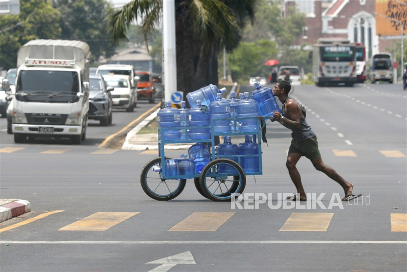 Seorang pria mendorong gerobak dengan botol air minum di jalan di Yangon, Myanmar.