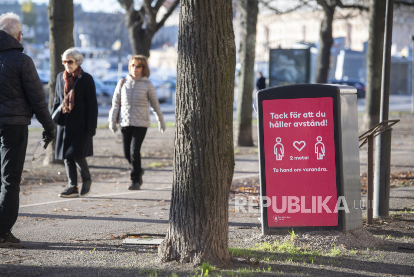  Orang-orang yang berjalan-jalan dalam cuaca dingin tapi cerah melewati tanda yang meminta untuk menjaga jarak sosial, di tengah penyebaran pandemi penyakit coronavirus (COVID-19) yang terus menerus, di Stockholm, Swedia, 20 November 2020. Pemerintah Swedia akan memberikan dosis ke-4 vaksin COVID-19 bagi lansia berusia 65 tahun ke atas. 