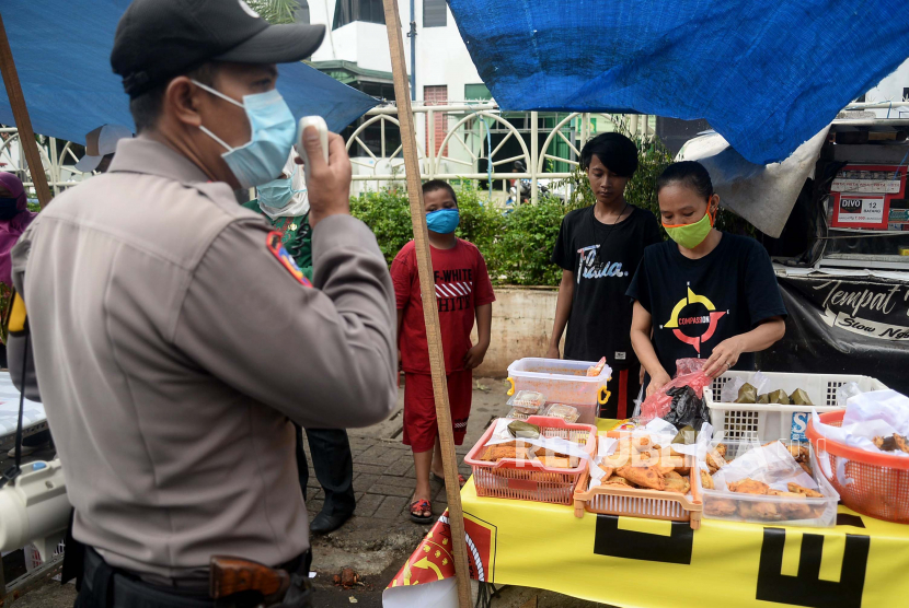Anggota Polisi memberikan himbauan kepada para pembeli dan pedagang makanan berbuka puasa atau takjil di Kawasan Benhil, Jakarta, Jumat (24/4). Aparat gabungan dari polisi dan Kelurahan setempat berkeliling memberikan himbauan kepada para pedagang dan pembeli agar tetap menjaga jarak serta wajib mengunakan masker