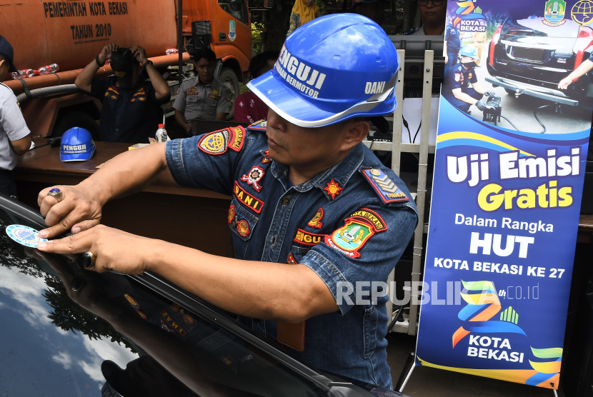 Petugas menempelkan stiker ke mobil yang lulus uji emisi di halaman kantor pemerintahan Kota Bekasi, Jawa Barat, Kamis (7/3/2024). Dinas Perhubungan Kota Bekasi menggelar uji emisi untuk mengetahui kadar gas buang kendaraan bermotor yang digunakan masyarakat dan untuk penanganan polusi udara. 