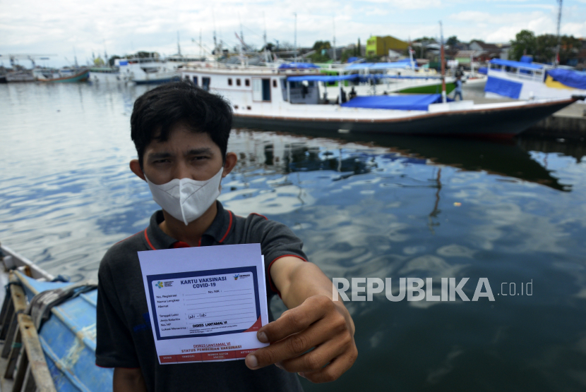 Warga memperlihatkan kartu vaksin usai mendapatkan suntikan vaksin Covid-19 di atas kapal nelayan.