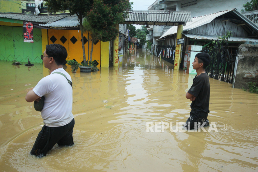 Warga melintasi jalan yang merendam salah satu perkampungan di Dayeuhkolot, Kabupaten Bandung, Jumat (12/1/2024). Banjir terjadi akibat luapan Sungai Citarum dan sungai-sungai yang bermuara ke Citarum. Ketinggian banjir mengakibatkan terputusnya akses jalan, karena tidak bisa dilalui kendaraan bermotor.