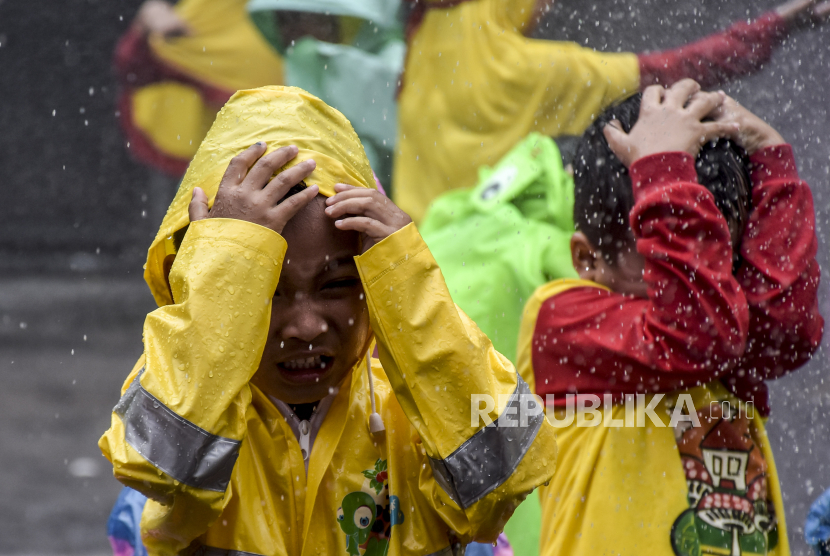 Sejumlah siswa mengenakan jas hujan di Kota Bandung, Jawa Barat.