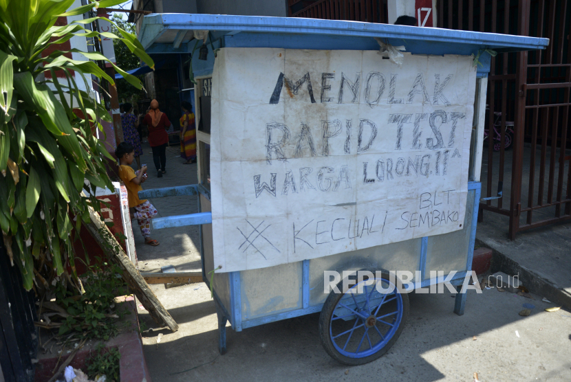Warga menutup jalan akses masuk lorong permukiman dengan gerobak yang terpasang spanduk penolakan mengikuti tes diagnostik cepat (Rapid Test) COVID-19 di Makassar, Sulawesi Selatan, Senin (8/6/2020). Penolakan rapid test dinilai akibat kurangnya sosialisasi bahaya Covid-19 di masyarakat.