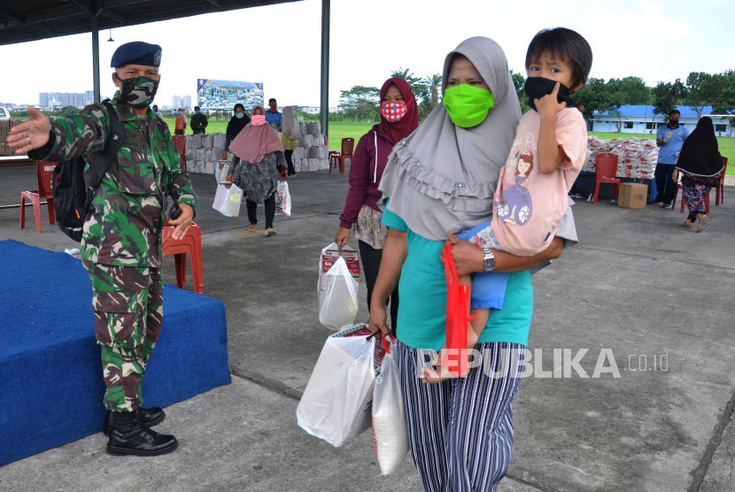 Sejumlah warga membawa paket sembako yang diberikan TNI AU di Lanud Soewondo, Medan, Sumatera Utara, Jumat (24/4/2020). Lanud Soewondo membagikan paket sembako gratis yang ditujukan bagi warga tidak mampu yang terdampak pandemi COVID-19