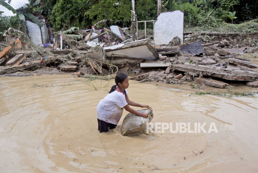  Seorang gadis muda mencuci bantal di air banjir dekat reruntuhan rumah di lingkungan yang terkena dampak banjir di Medan, Sumatera Utara, Jumat (4/12/2020). Hujan deras di kota terbesar ketiga negara itu membanjiri sungai dan membanjiri ribuan orang rumah meninggalkan sejumlah orang tewas dan hilang.