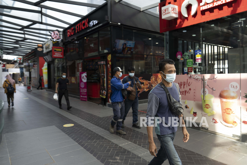 Warga dengan mengenakan masker berjalan di luar pusat perbelanjaan di Kuala Lumpur, Malaysia, Kamis (14/1). 