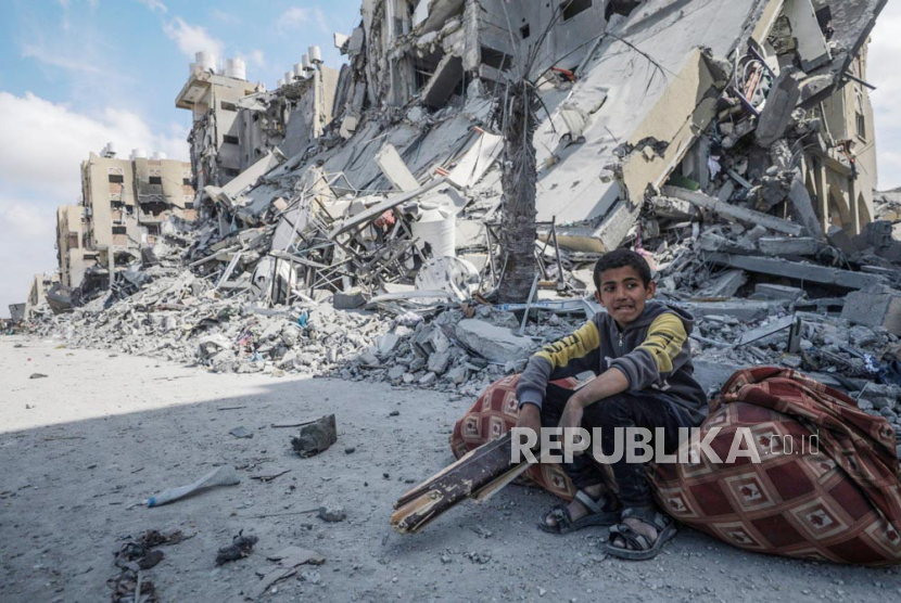 Seorang anak laki-laki Palestina duduk di samping puing-puing rumah yang hancur di kota menara Hamad setelah operasi militer Israel di kota Khan Younis, Jalur Gaza selatan, 14 Maret 2024.