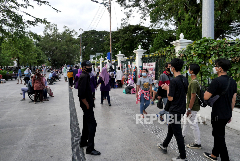 Petugas berjaga mengawasi penggunaan masker pengunjung di kawasan Titik Nol Yogyakarta, Ahad (21/3). Survei opini publik nasional SMRC menunjukkan 27 persen warga tidak takut tertular Covid-19.