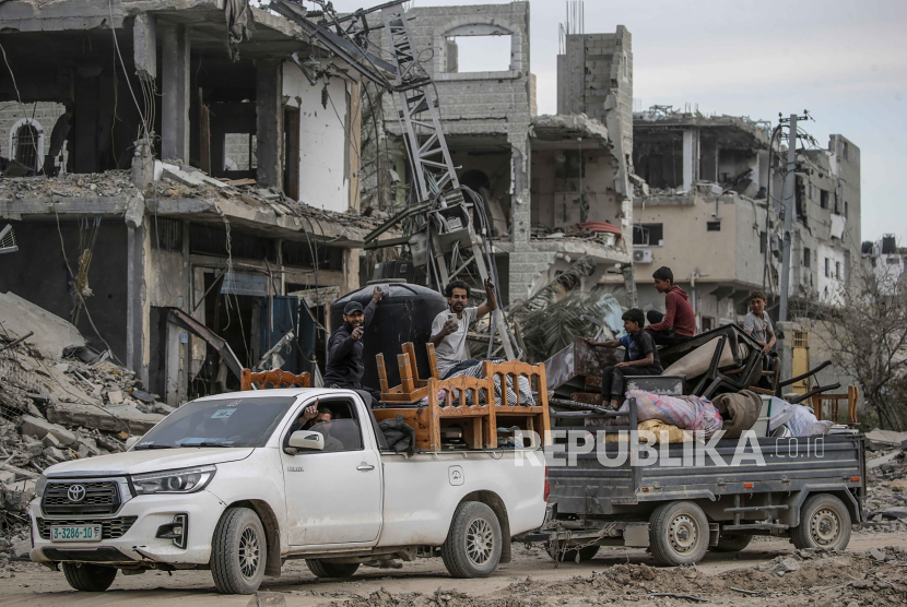 Warga Palestina mengendarai kendaraan yang memuat barang-barang mereka melewati puing-puing rumah yang hancur pasca operasi militer Israel di Khan Younis, Jalur Gaza selatan, 8 April 2024. 