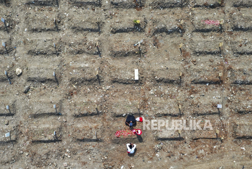 Sebuah foto yang diambil dengan drone menunjukkan kerabat berdoa di atas kuburan korban COVID-19 di pemakaman Srengseng Sawah di Jakarta, Indonesia, 26 Maret 2021. 