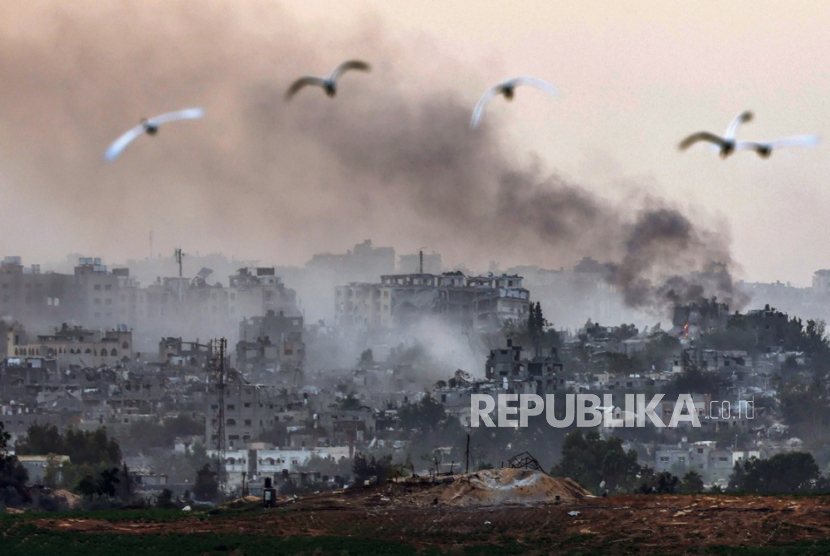 Burung melintas saat asap mengepul dari bagian utara Jalur Gaza akibat serangan Israel, Ahad (29/10/2023.
