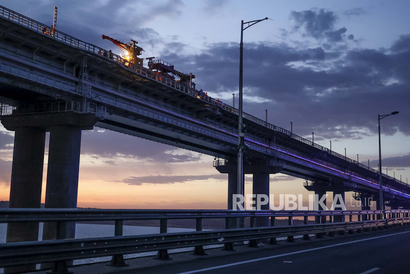 Pekerja memperbaiki bagian rel dari Jembatan Krimea yang menghubungkan daratan Rusia dan semenanjung Krimea di atas Selat Kerch, di Kerch, Krimea, Sabtu, 8 Oktober 2022.