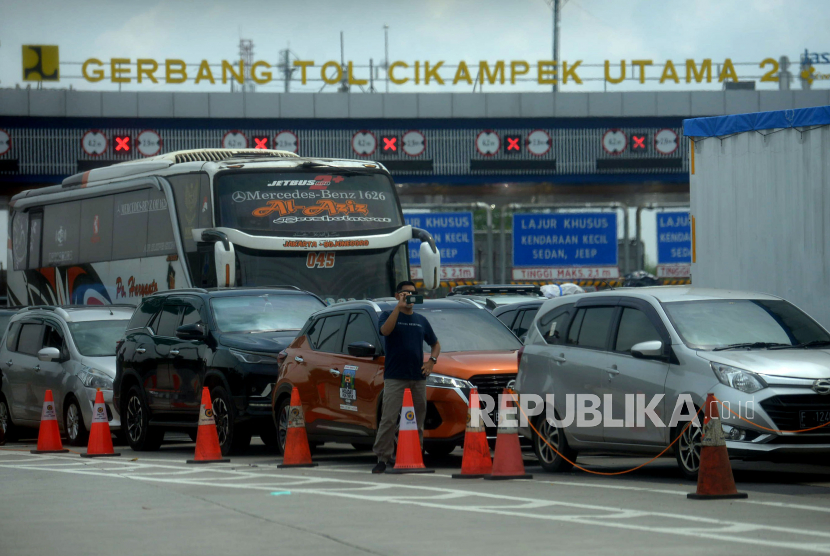 Pemudik keluar dari kendaraannya ketika terjebak kemacetan di Gerbang Tol Cikampek Utama, Purwakarta, Jawa Barat, Sabtu (30/4/2022). 