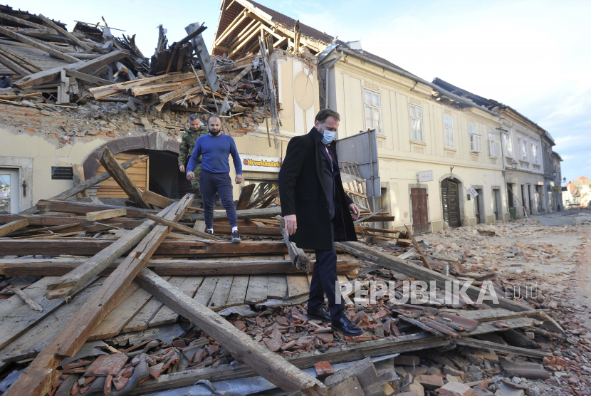 Orang-orang melewati sisa-sisa bangunan yang rusak akibat gempa bumi, di Petrinja, Kroasia, Selasa, 29 Desember 2020