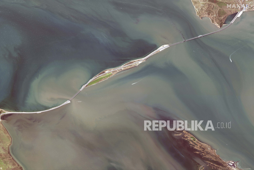 Gambar satelit yang disediakan oleh Maxar Technologies ini menunjukkan kerusakan pada Jembatan Kerch, yang menghubungkan Semenanjung Krimea, kanan atas, dengan Rusia, kiri bawah, melintasi selat antara Laut Hitam dan Laut Azov, dan gerbong terbakar, kanan atas , pada hari Sabtu, 8 Oktober 2022. 