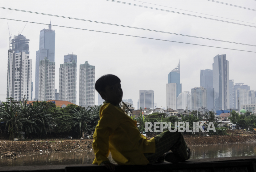 Anak-anak duduk dengan latar belakang gedung bertingkat yang diselimuti kabut polusi di Jakarta, Jumat (1/4/2022). Berdasarkan situs IQAi, indeks kualitas udara di Jakarta berada di level 114 AQI US dengan particulate matter (PM) 2,5 dan berada di urutan kota urutan ke-10 dengan kualitas udara terburuk di dunia pada hari ini. Republika/Putra M. Akbar