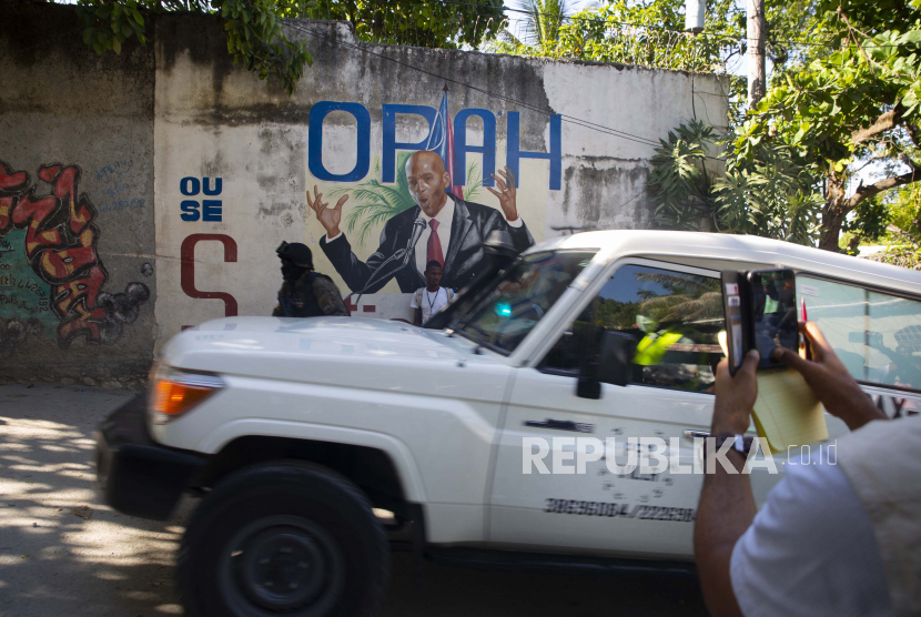 Ambulans yang membawa jenazah Presiden Haiti Jovenel Moise melewati mural yang menampilkan dirinya di dekat kediaman pemimpin di mana dia dibunuh oleh orang-orang bersenjata di pagi hari di Port-au-Prince, Haiti, Rabu, 7 Juli 2021.