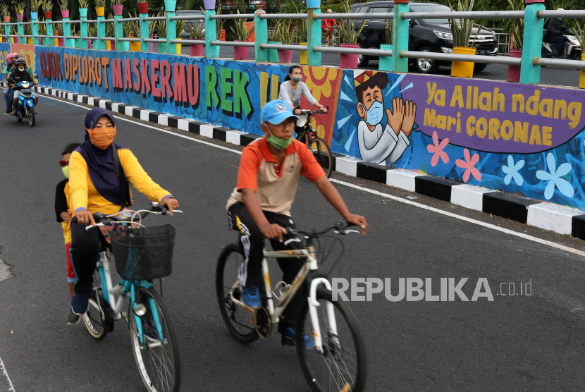 Sejumlah pesepeda melintas di dekat dinding bermural di Surabaya, Jawa Timur. Sekitar 63 kelurahan di Kota Surabaya, Jawa Timur, per 21 Oktober 2020 dinyatakan nol kasus terkonfirmasi virus corona jenis baru atau Covid-19. 