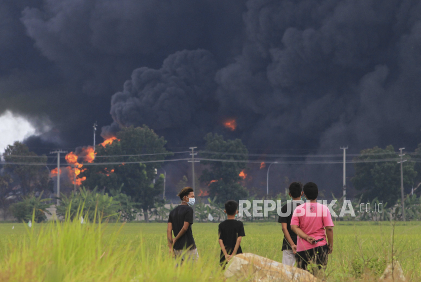  Orang-orang melihat kilang minyak yang terbakar saat kebakaran di kilang minyak Balongan milik negara di Balongan, Indramayu, Indonesia, 29 Maret 2021.