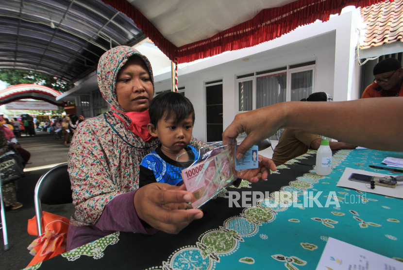Petugas menyerahkan Bantuan Sosial Tunai bagi warga di Kantor Pos Indramayu, Jawa Barat, Ahad (9/5/2020). Penyaluran Bantuan Sosial Tunai (BST) dari Kemensos berupa uang tunai senilai Rp600