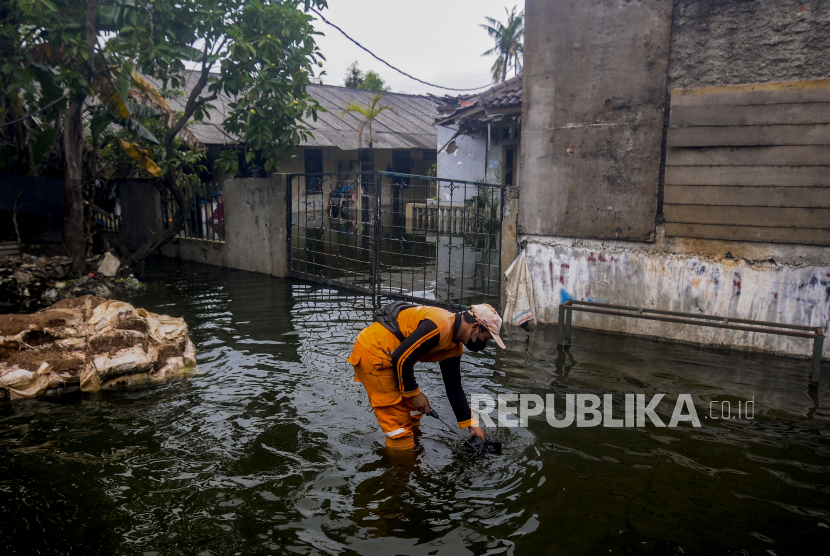 Petugas Satpol PP membersihkan sampah saat terjadi banjir di kawasan Duren Sawit, Jakarta Timur. Pemkot Jakarta Timur mengeklaim lokasi banjir di daerahnya berkurang 13 titik.