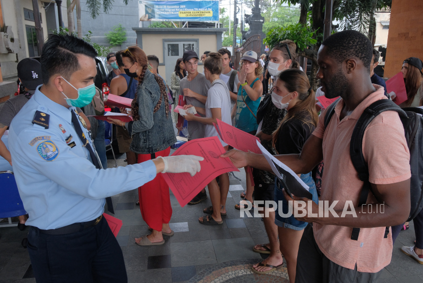 Petugas imigrasi memeriksa dokumen warga negara asing (WNA) saat mereka antre mengurus perpanjangan visa dan permohonan izin tinggal di Kantor Imigrasi Kelas I Khusus Ngurah Rai, Badung, Bali, Senin (23/3/2020). 