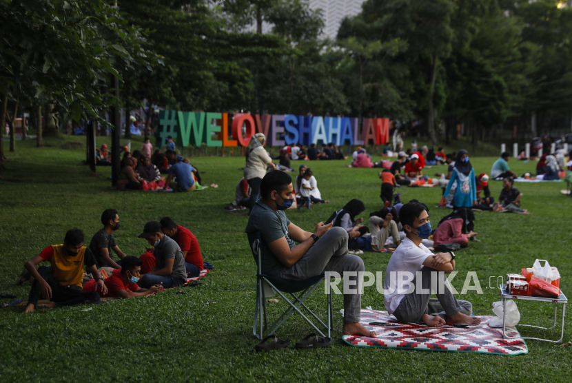 Ulama Malaysia Beri Konseling Gratis Hadapi Stres Pandemi. Muslim Malaysia menjaga jarak sosial dan mengenakan masker pelindung wajah saat mereka menunggu berbuka puasa di depan masjid di taman umum di Shah Alam, di luar Kuala Lumpur, Malaysia, 25 April 2021. 