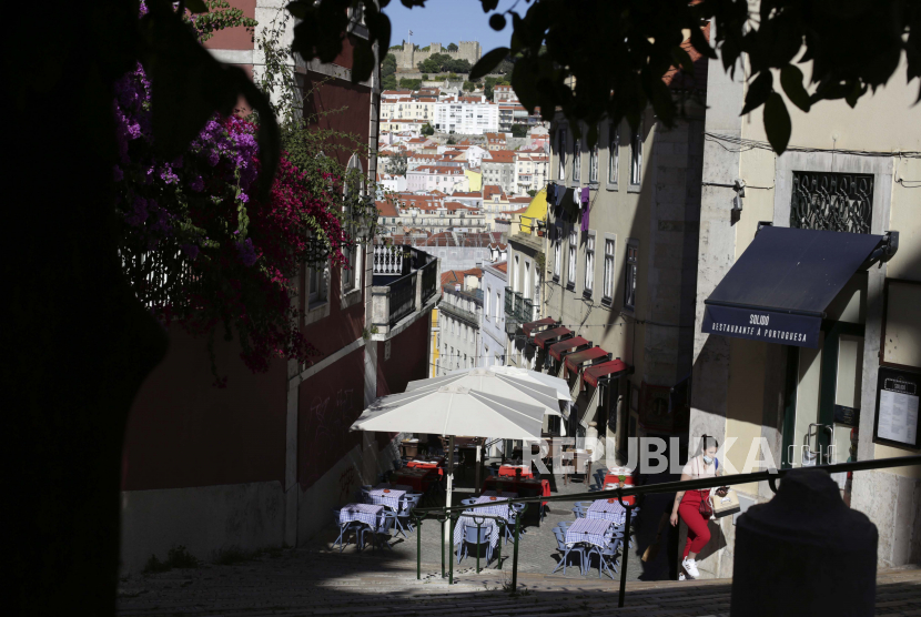 Seorang wanita menaiki tangga menuju Bairro Alto, atau High Quarter, Lisbon, Kamis, 1 Juli 2021. Virus corona menjadi penyebab 9,6 persen kematian di Portugal sepanjang 2021