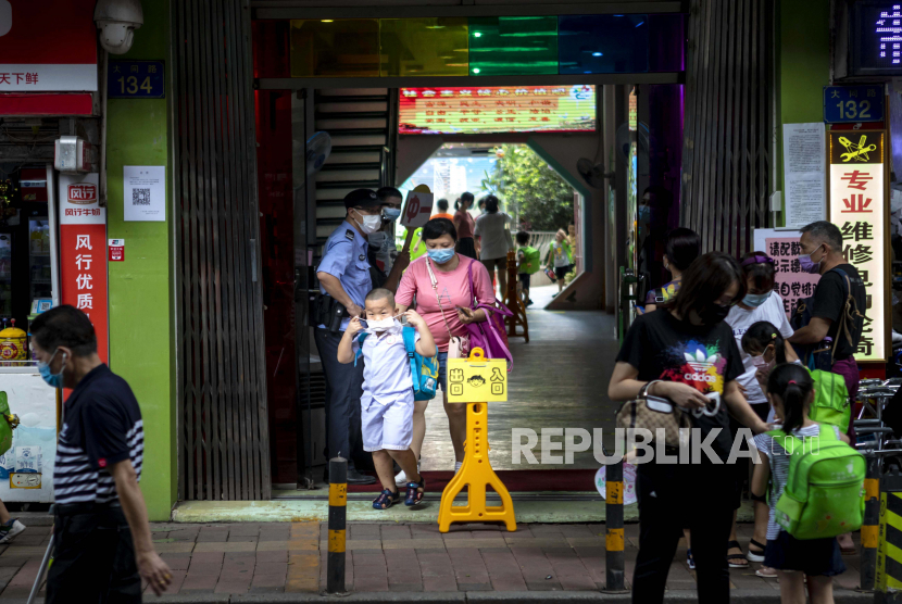 Seorang wanita menjemput anaknya dari sekolah di Guangzhou, China, Senin (22/6). 