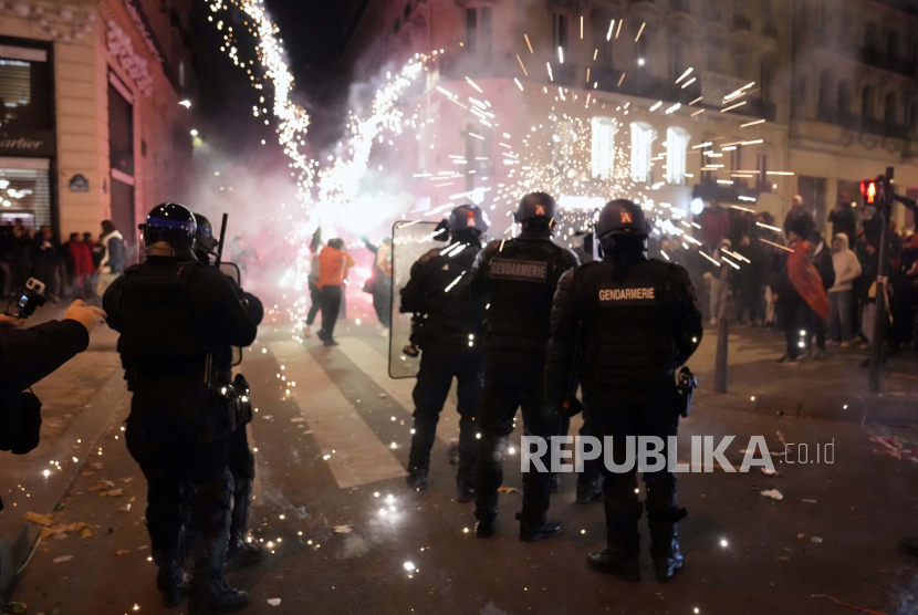 Polisi Prancis berdiri di dekat api setelah pertandingan sepak bola perempat final Piala Dunia di Champs Elysee Avenue, di Paris, Sabtu, 10 Desember 2022. Prancis Kerahkan 10 Ribu Polisi Jelang Semifinal Piala Dunia Melawan Maroko