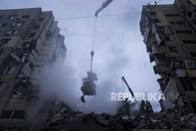 Petugas membersihkan puing-puing setelah roket Rusia menghantam gedung bertingkat di kota Dnipro, Ukraina, Ahad, (15/1/2023). NATO Desak Sekutu Kirim Lebih Banyak Senjata Berat untuk Ukraina