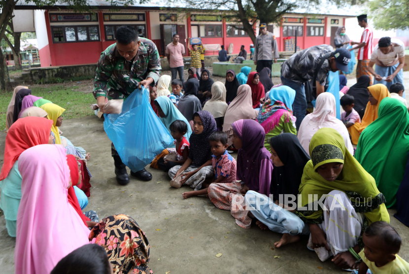Personel militer mendistribusikan makanan untuk pengungsi Rohingya di tempat penampungan sementara yang disediakan oleh pemerintah daerah Aceh, di Pidie, Aceh, Indonesia, 28 Desember 2022. Polisi setempat mengatakan bahwa 174 migran etnis Rohingya mendarat di Pantai Laweung Pidie, Provinsi Aceh di Indonesia pada 26 Desember , setelah dilaporkan berlayar selama berminggu-minggu di laut. Menurut pernyataan yang dikeluarkan pada 27 Desember oleh Badan Pengungsi PBB (UNHCR), lebih dari 200 orang dibawa ke pantai dengan aman di barat laut Indonesia selama beberapa hari terakhir. Dua kelompok, sekitar 58 pada 25 Desember, dan 174, termasuk mayoritas wanita dan anak-anak, pada 26 Desember, diselamatkan dan diturunkan oleh nelayan Indonesia dan pihak berwenang setempat, tambah UNHCR.