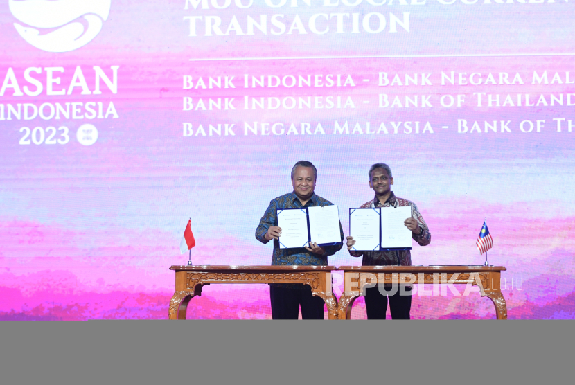 Gubernur Bank Indonesia Perry Warjiyo (kiri) bersama Gubernur Bank Negara Malaysia Abdul Rasheed Ghaffour menunjukan berkas kesepakatan kerja sama (MoU) di Jakarta, Jumat (25/8/2023). Bank Indonesia, Bank Negara Malaysia, dan Bank of Thailand menyepakati untuk memperkuat kerja sama guna mendorong penggunaan mata uang lokal masing-masing negara dalam transaksi di negara Indonesia, Malaysia dan Thailand.  