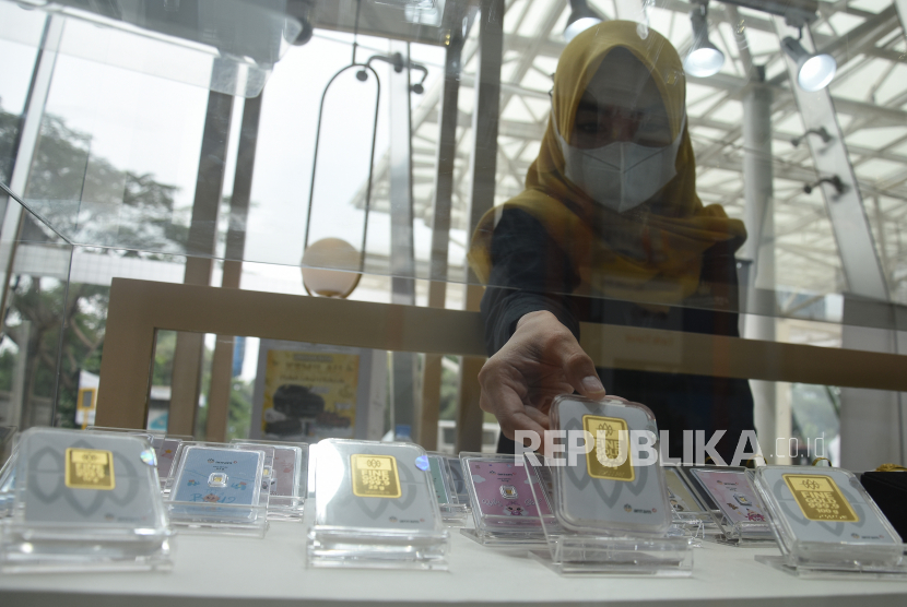 Seorang pegawai menunjukkan kepingan emas di gerai penjualan emas di Gedung Antam, Jakarta, Selasa (12/7/2022). 