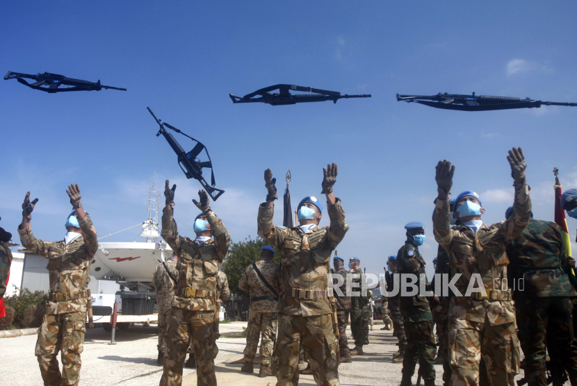 Pasukan penjaga perdamaian PBB Indonesia melemparkan senapan mereka ke udara selama upacara untuk menandai pengalihan wewenang antara yang keluar dan kepala misi yang baru diangkat di markas UNIFIL di kota selatan Lebanon Naqoura, Lebanon, Senin, 28 Februari 2022 .
