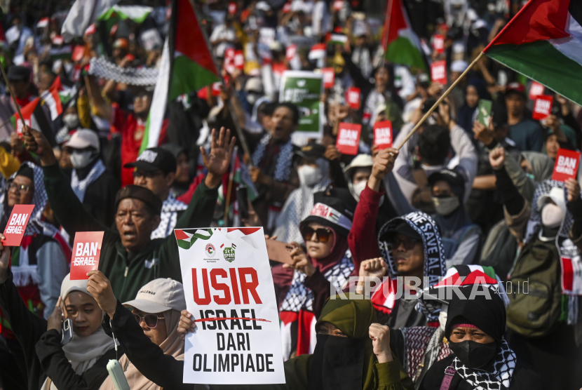 Pengunjuk rasa mengangkat kartu merah simbol tuntutan pemboikotan Israel di Olimpiade Paris di kawasan Patung Arjuna Wiwaha, Jakarta, Ahad (21/7/2024).