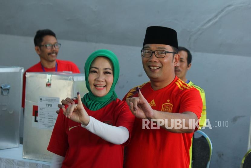 Calon Gubernur Jawa Barat Ridwan Kamil bersama istri Atalia Praratya menunjukan tinta di jari kelingking usai mencoblos dalam Pilkada Serentak 2018, di Tempat Pemungutan Suara (TPS) 21, Cigadung, Kota Bandung, Rabu (27/6).
