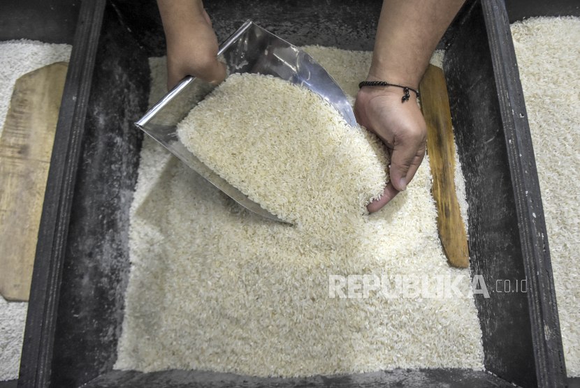 Pedagang menunjukkan beras yang dijual di kiosnya.
