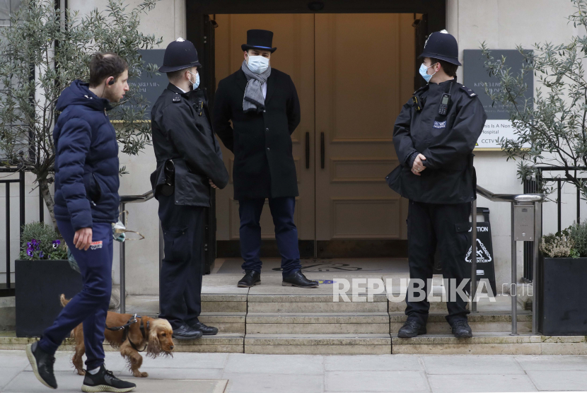  Seorang pria berjalan dengan seekor anjing ketika petugas polisi berdiri di luar rumah sakit Raja Edward VII di London, Selasa, 23 Februari 2021. Pangeran Philip dari Inggris dirawat di Rumah Sakit swasta Raja Edward VII di London pada Selasa, 16 Februari 2021.