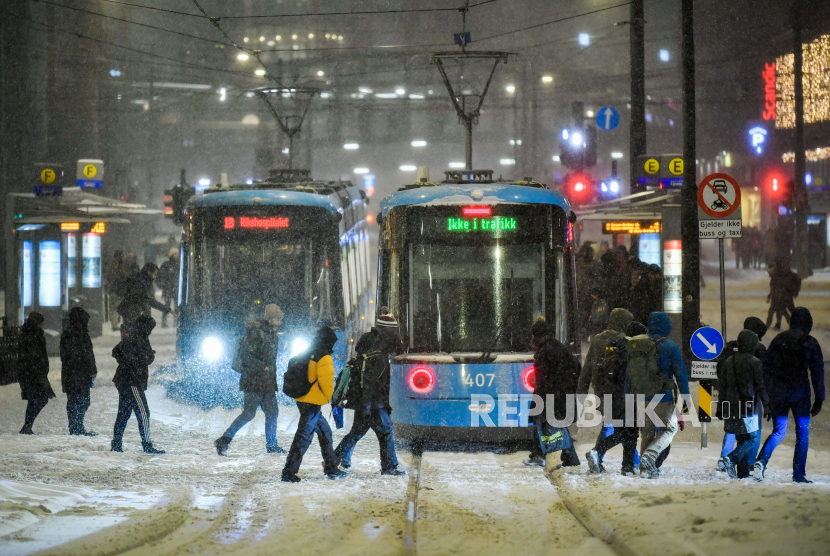 Para komuter berjalan dengan trem dan bus selama badai salju di Jernbanetorget di pusat Oslo, Norwegia, Rabu, 4 Januari 2023. Oslo tidak akan Lagi Beli Produk Hasil Tanah Pendudukan Israel