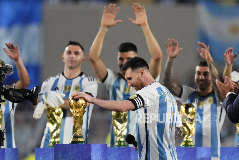  Pelatih timnas Argentina Lionel Messi menyentuh trofi Piala Dunia FIFA saat perayaan untuk para penggemar. 