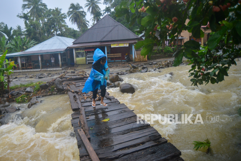 Warga melintasi jembatan kayu usai diterjang banjir bandang di Kuliek, Nagari Sungai Buluah Timur, Kabupaten Padangpariaman, Sumatera Barat, Kamis (30/9/2021). BPBD Padangpariaman mencatat, banjir bandang terjadi di daerah itu disebabkan hujan berintensitas tinggi sejak Rabu (29/9/2021), sementara di sejumlah titik di Padangpariaman terjadi banjir dan longsor. 